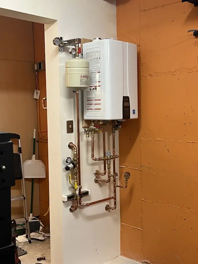 Plumbing technician inspecting water heater connections in East Aurora